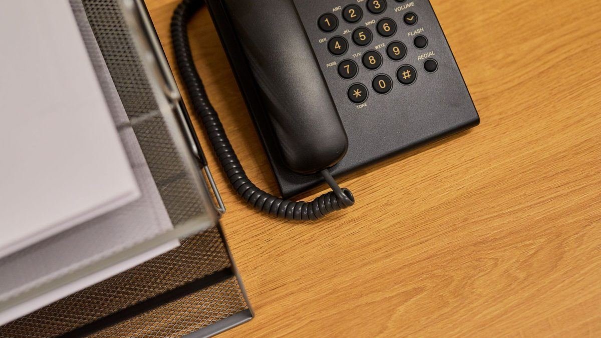 A desk telephone and document tray on an office desk