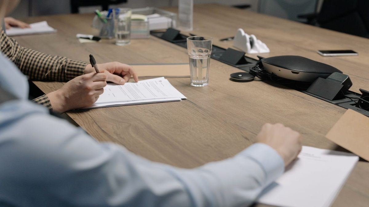 Two people reviewing and signing a contract at a meeting table